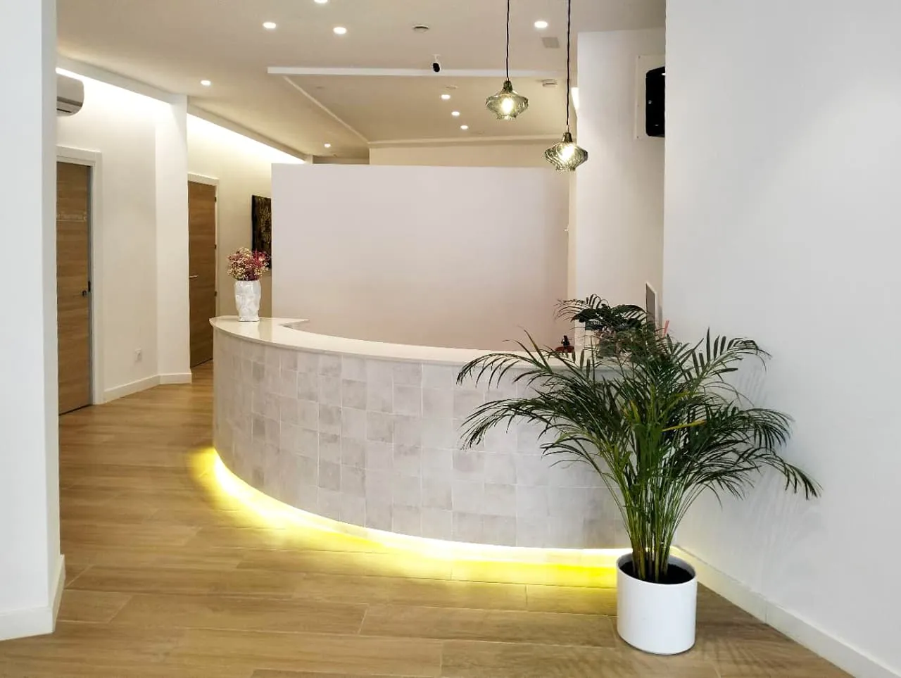 Recepción de Asoden Clínica Dental en Vigo, con mostrador curvo iluminado y planta